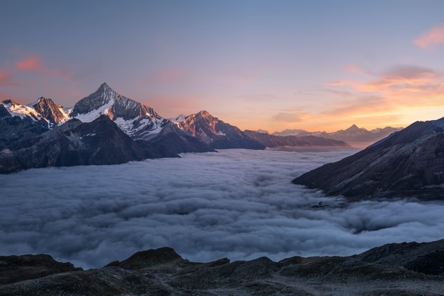 A layer of clouds floats between mountain peaks on the left and the right.